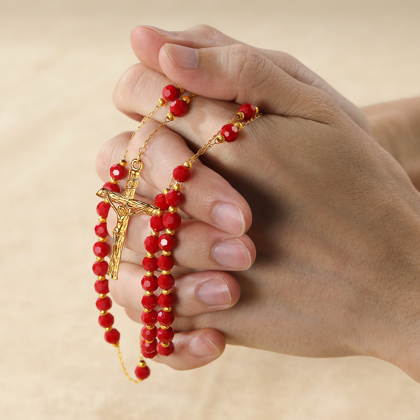Red bead rosary held in hands, Catholic religious jewelry