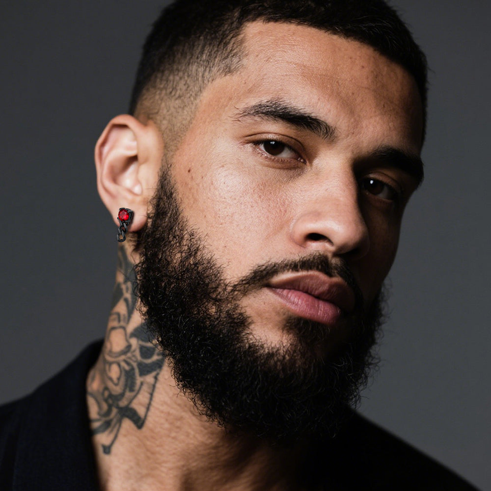 Man with tattoos and a beard wearing a black shirt against a dark background