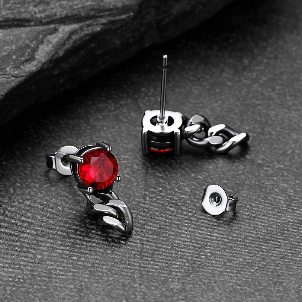Silver earrings with red gemstones on a dark surface