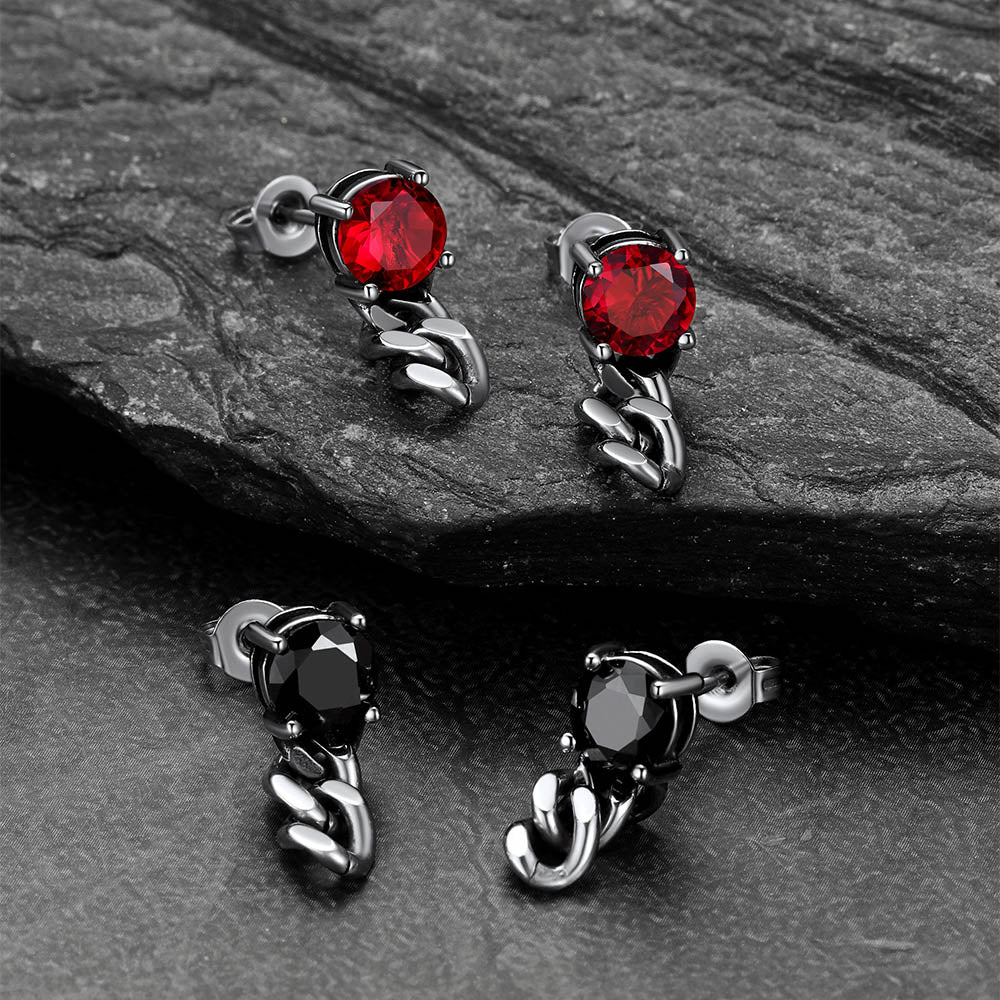 Pair of earrings with red and black gemstones on a stone surface