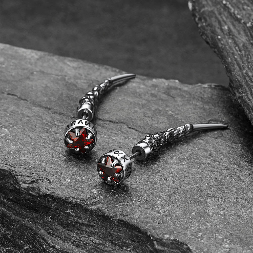 Pair of silver and red stone earrings on a dark stone surface
