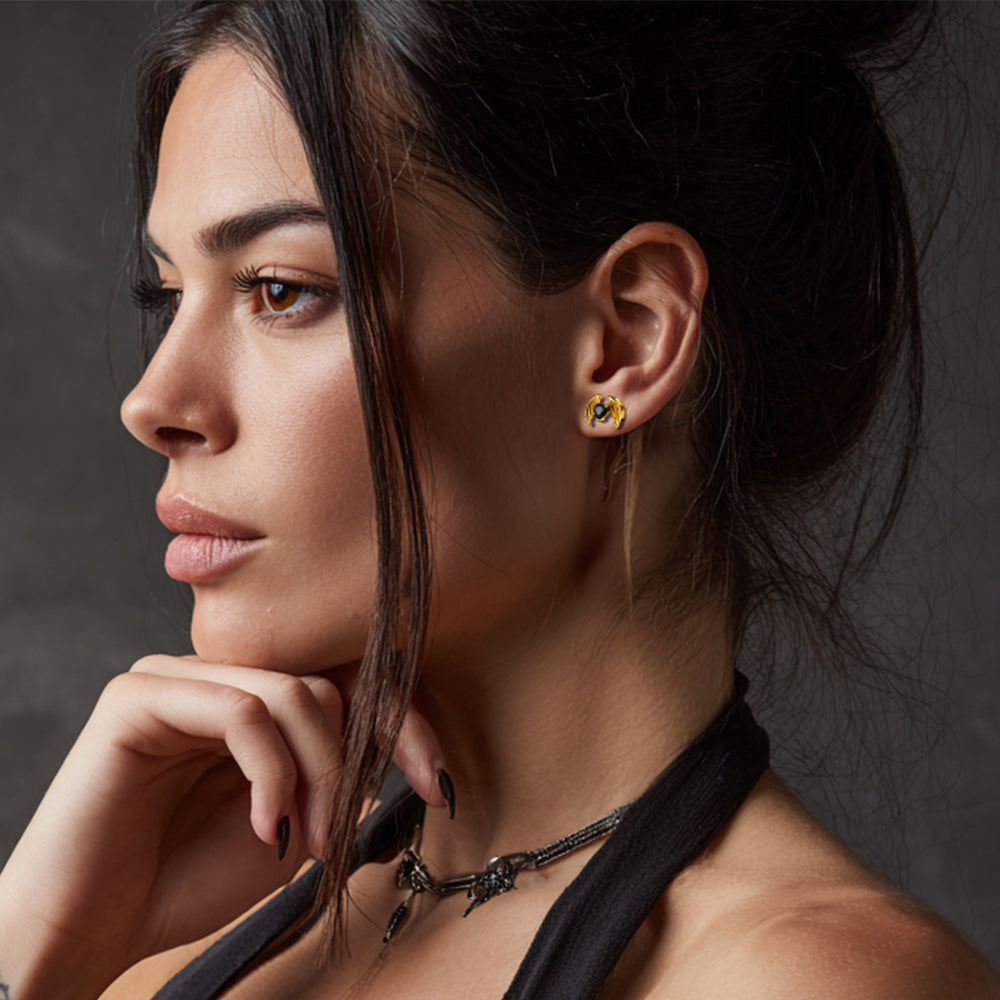 Close-up of a woman wearing earrings and a necklace against a dark background