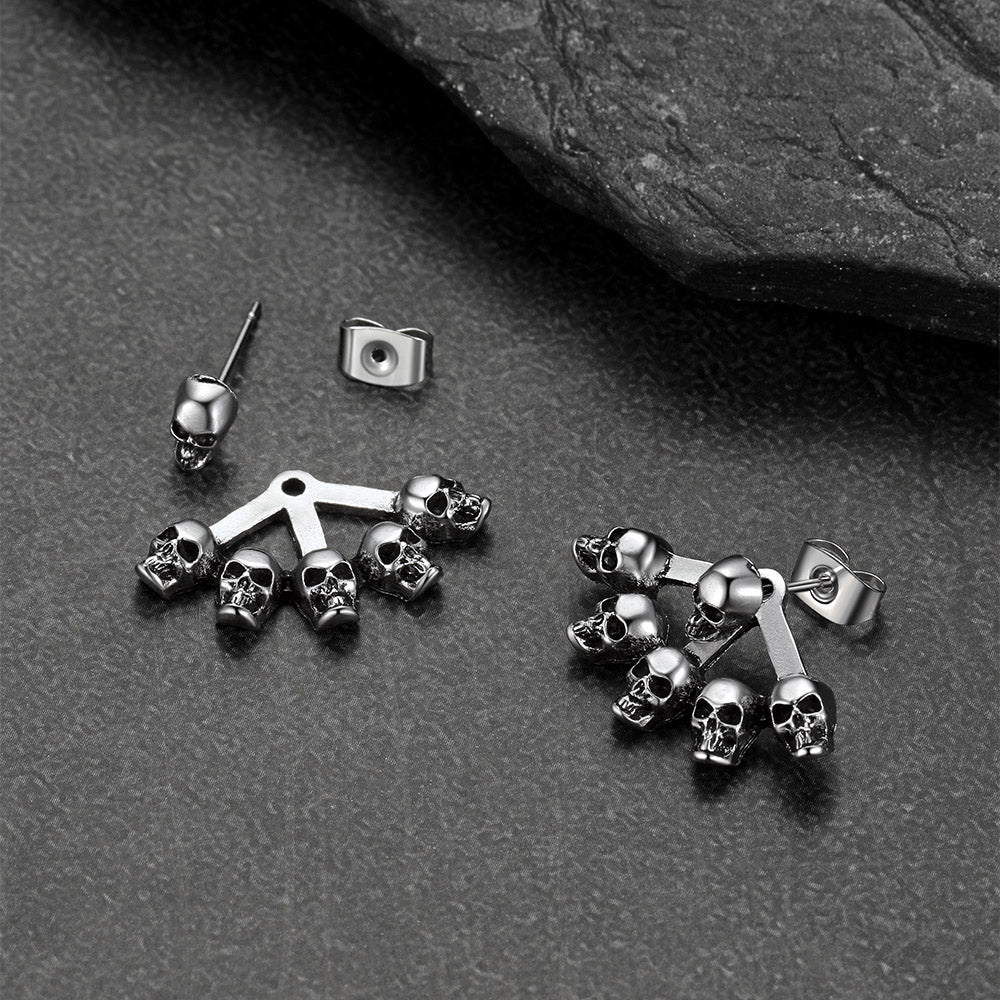 Silver skull-themed earrings on a dark surface