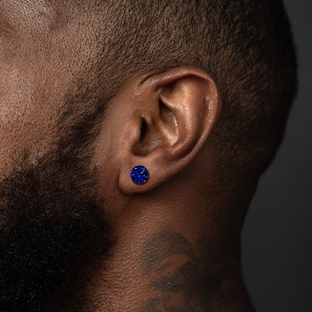 Close-up of an ear wearing a blue gemstone earring against a dark background