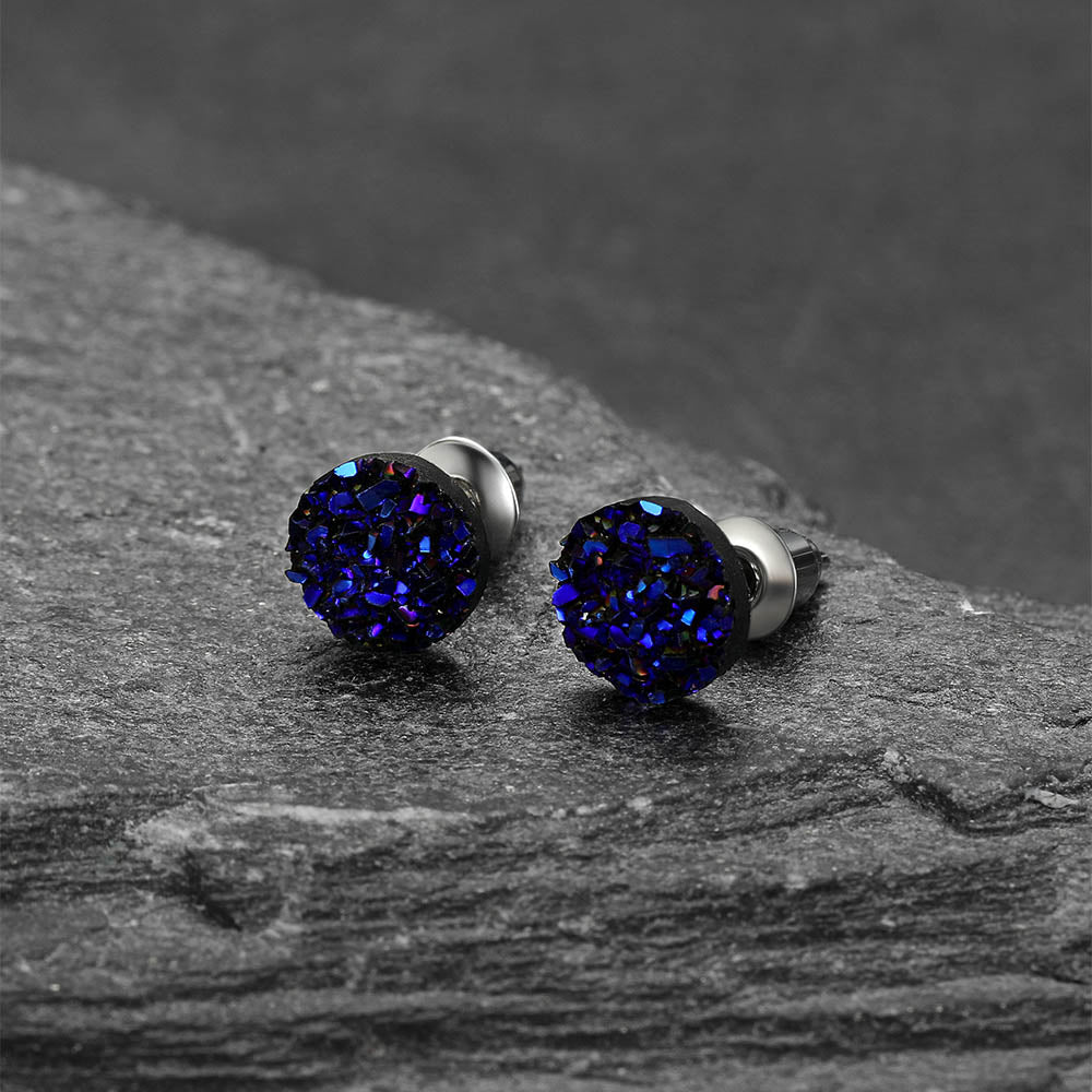 Pair of blue druzy stud earrings on a dark stone surface