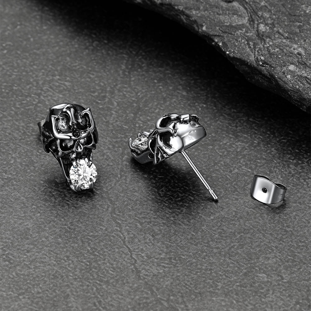 Stainless steel cubic zirconia skull earrings displayed on dark background.