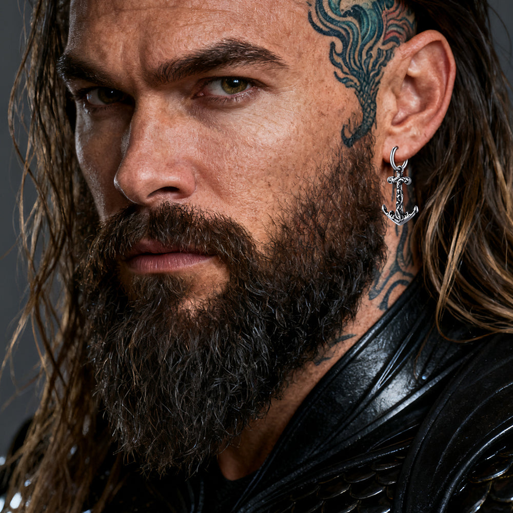 Close-up of a man with tattoos and a beard wearing an anchor earring.