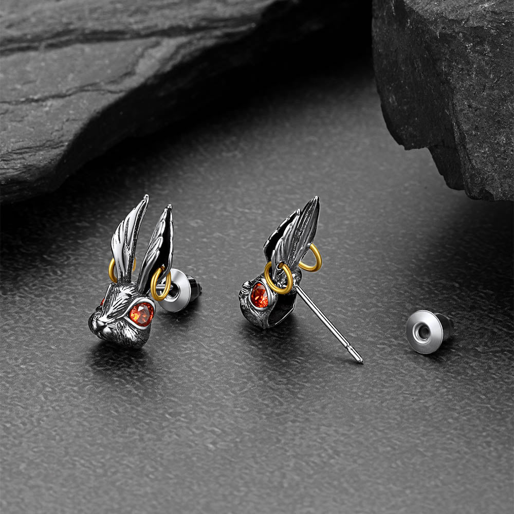 Silver earrings with red stones on a dark stone surface