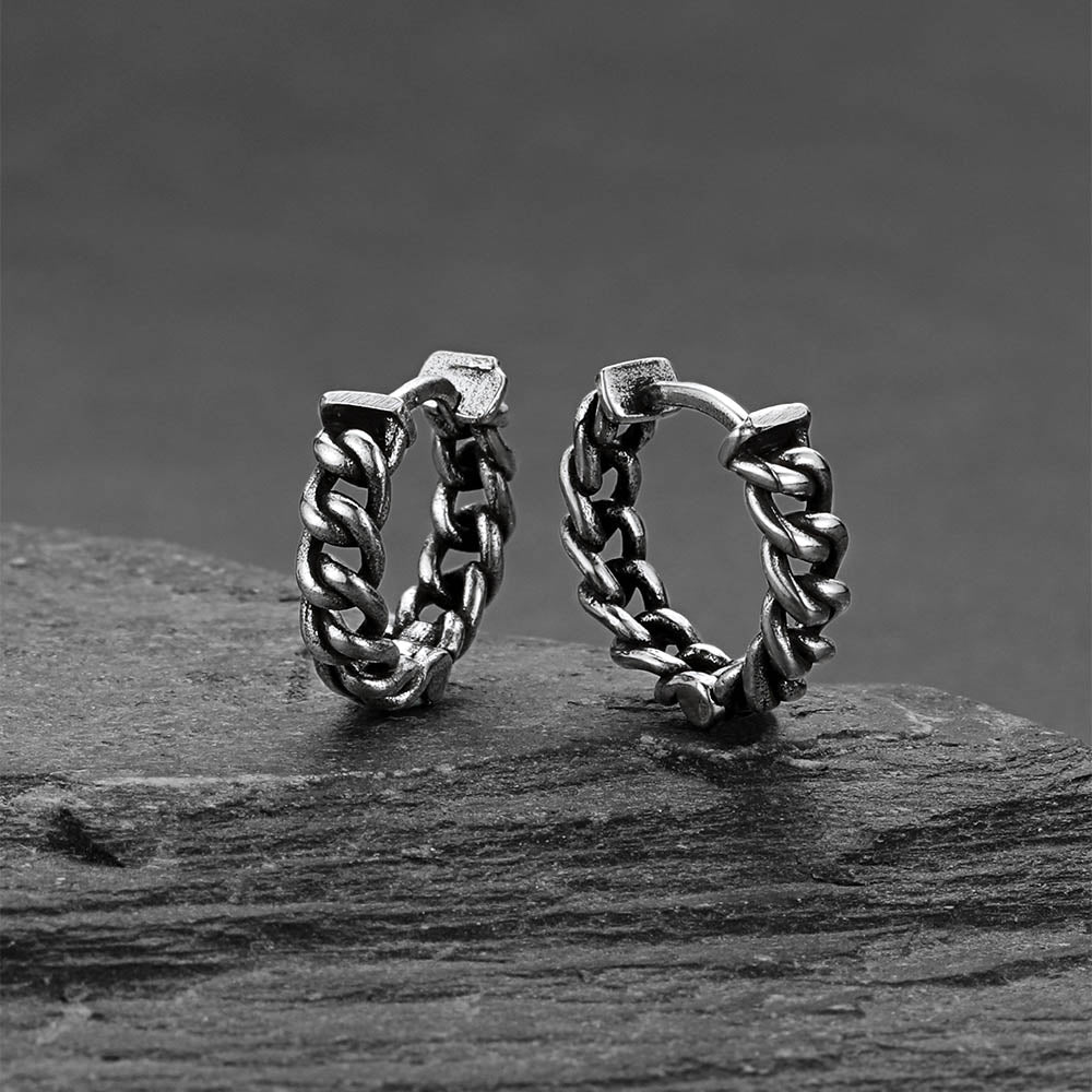 Pair of silver hoop earrings on a dark surface with a dark background