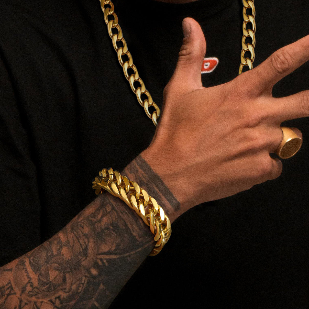 Person wearing a gold chain necklace and bracelet with a black background