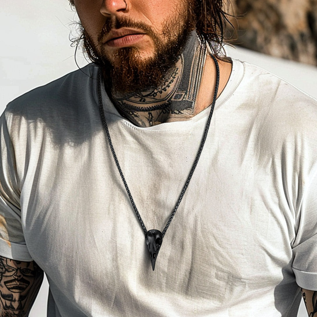 Man with tattoos and a beard wearing a white t-shirt against a mountainous background