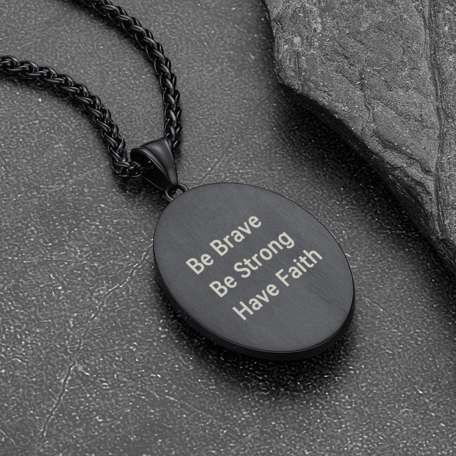 Black pendant necklace with motivational message on a dark surface