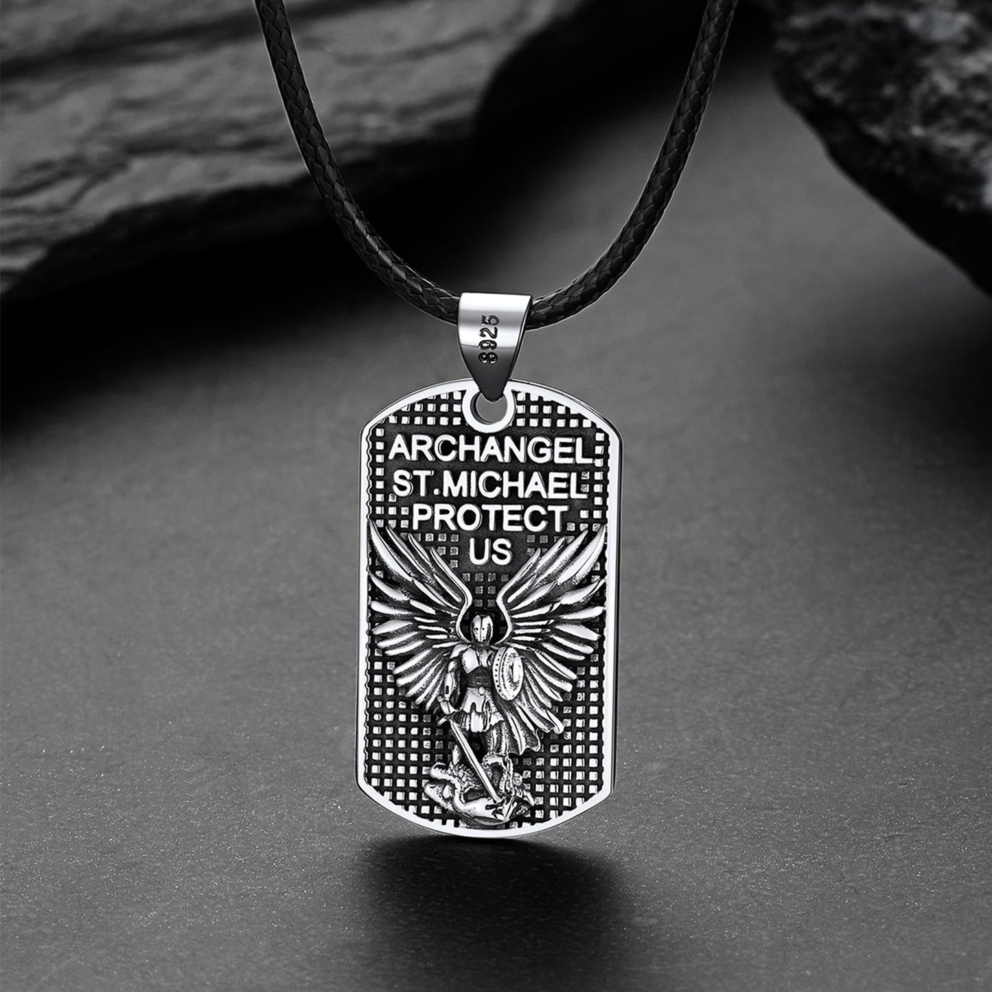 Silver pendant with angelic design and text on a dark surface