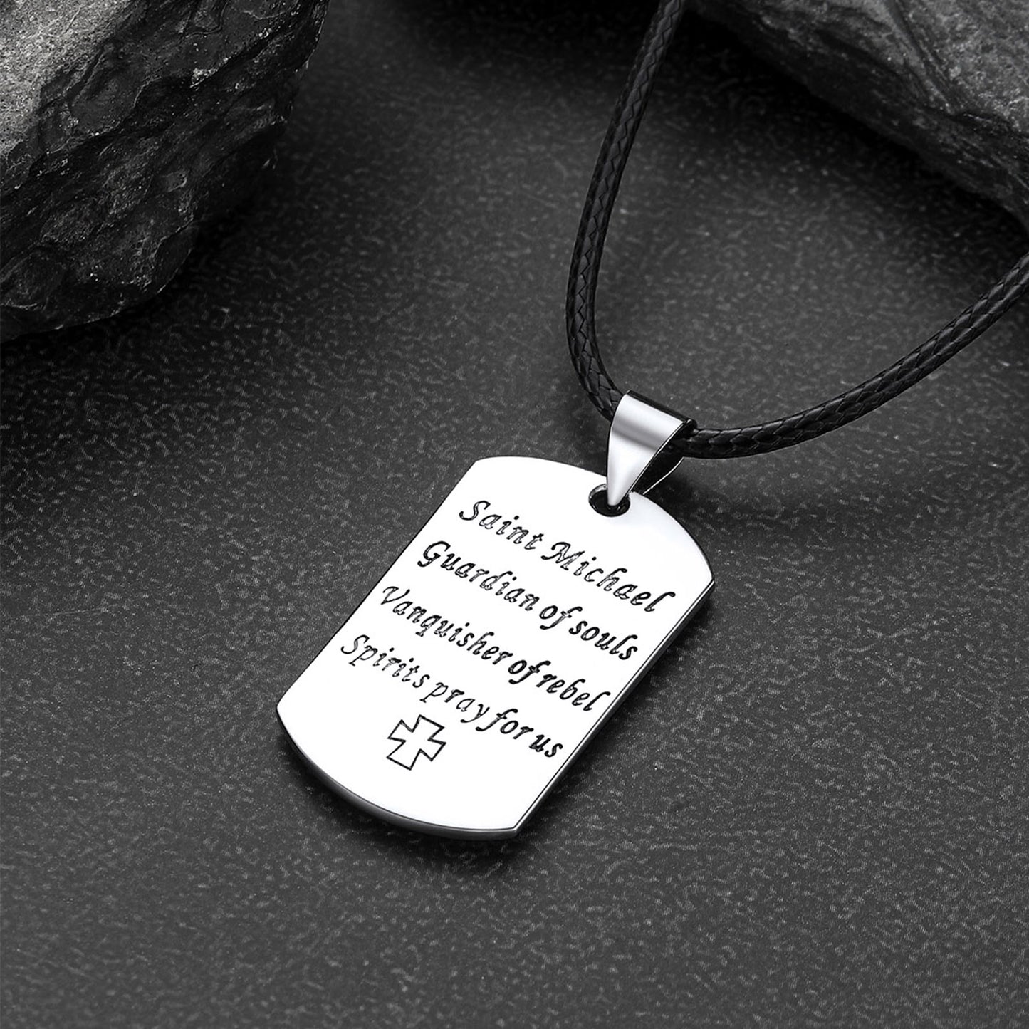 Dog tag pendant with engraved text on a dark surface