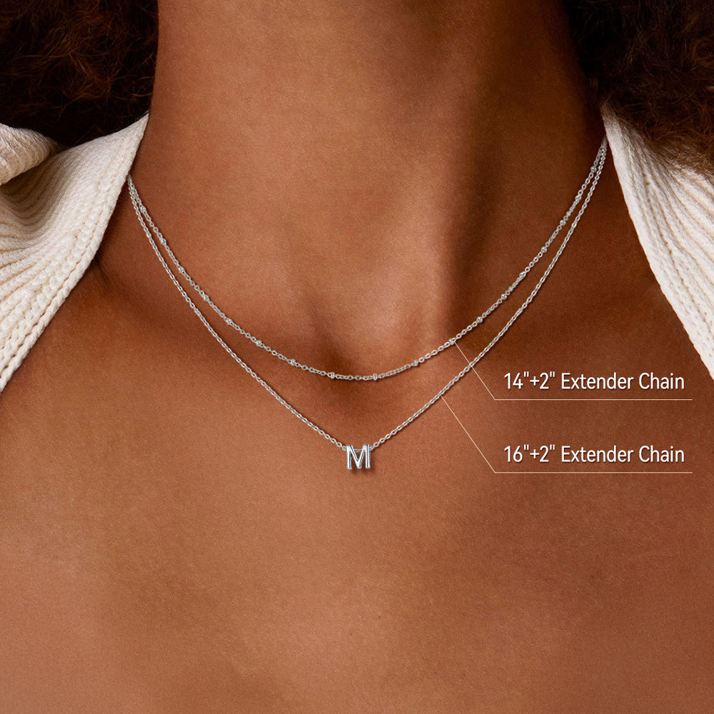 Woman wearing gold layered initial necklace with casual outfit and soft makeup