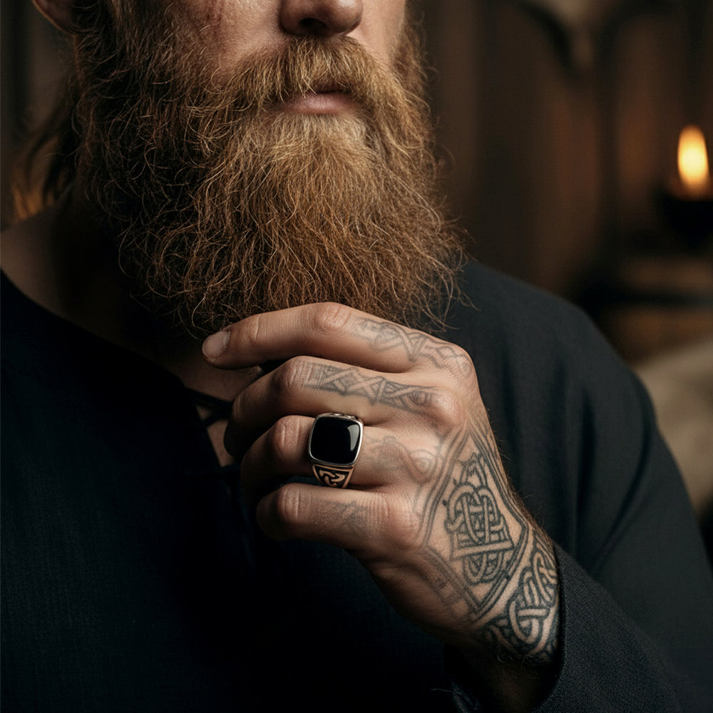 Man with a beard and tattooed hand wearing a Black Onyx Celtic Knot Signet Square Ring