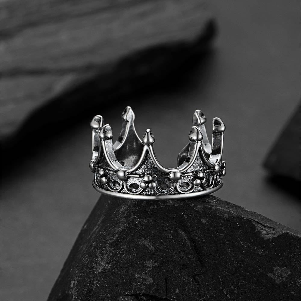 Silver crown-shaped ring on a dark stone surface