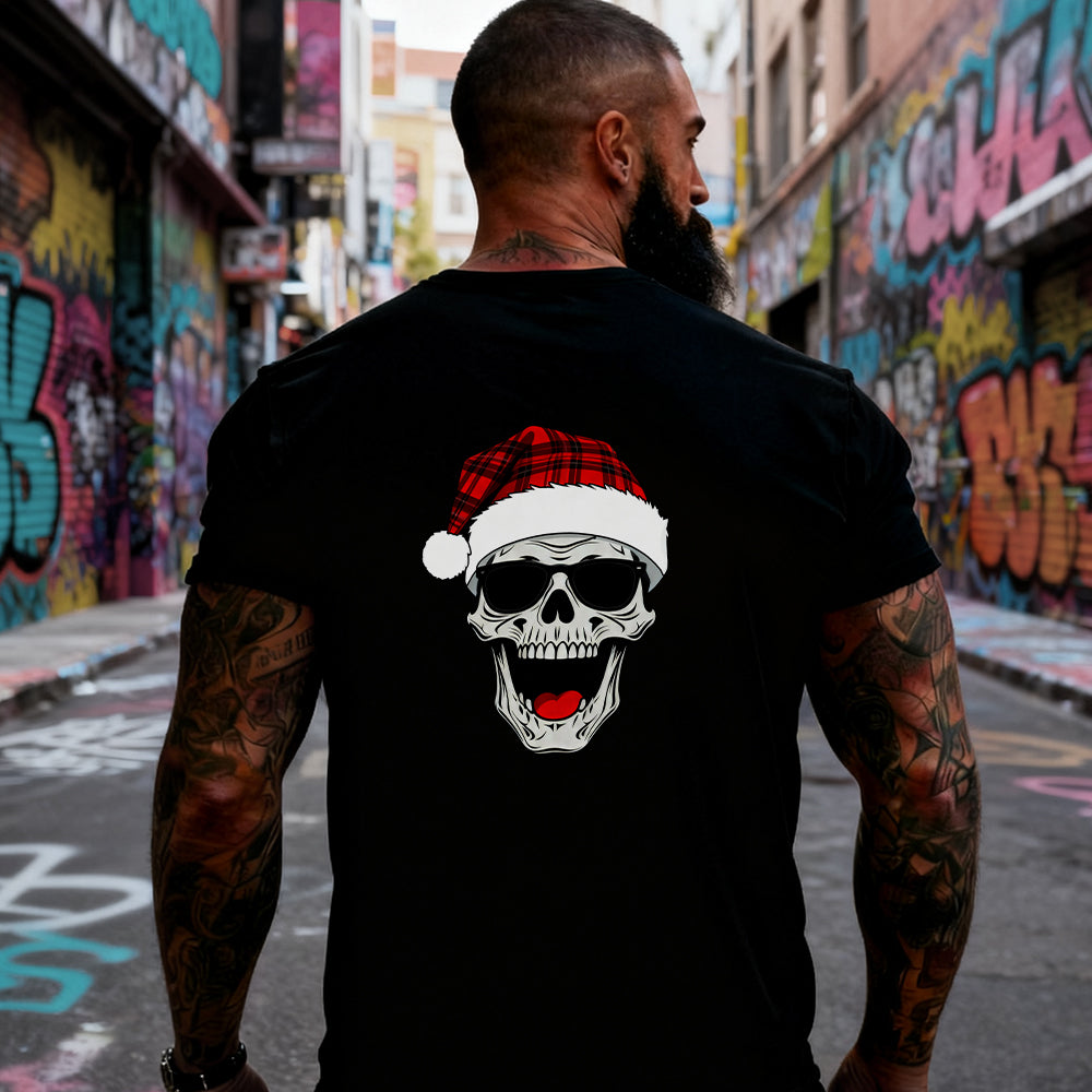 Man wearing a black t-shirt with a skull wearing a Santa hat graphic in an urban setting with graffiti.