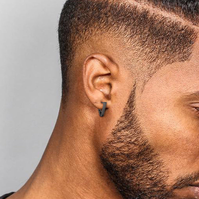 Black triangle hoop earring on a man's ear, representing strength and style.