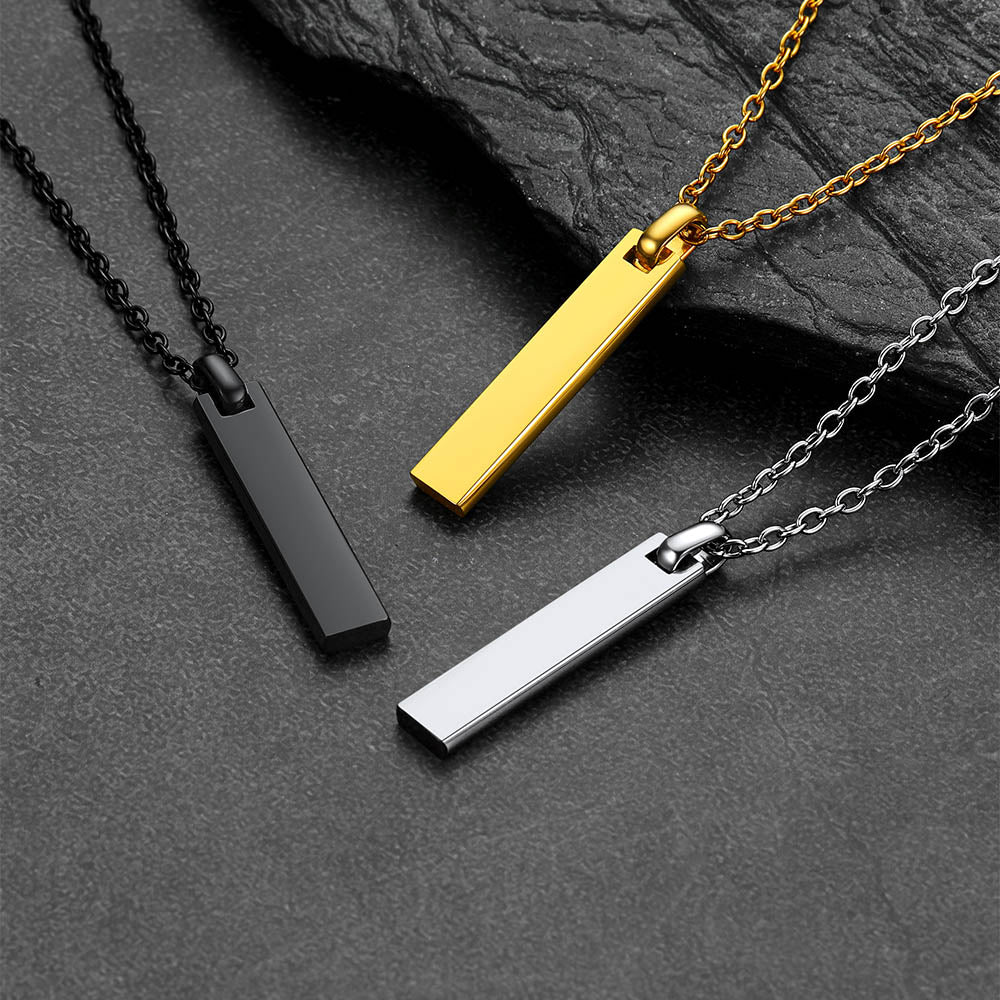 Three bar necklace with vertical bar pendants in gold, black, and silver on a dark surface.