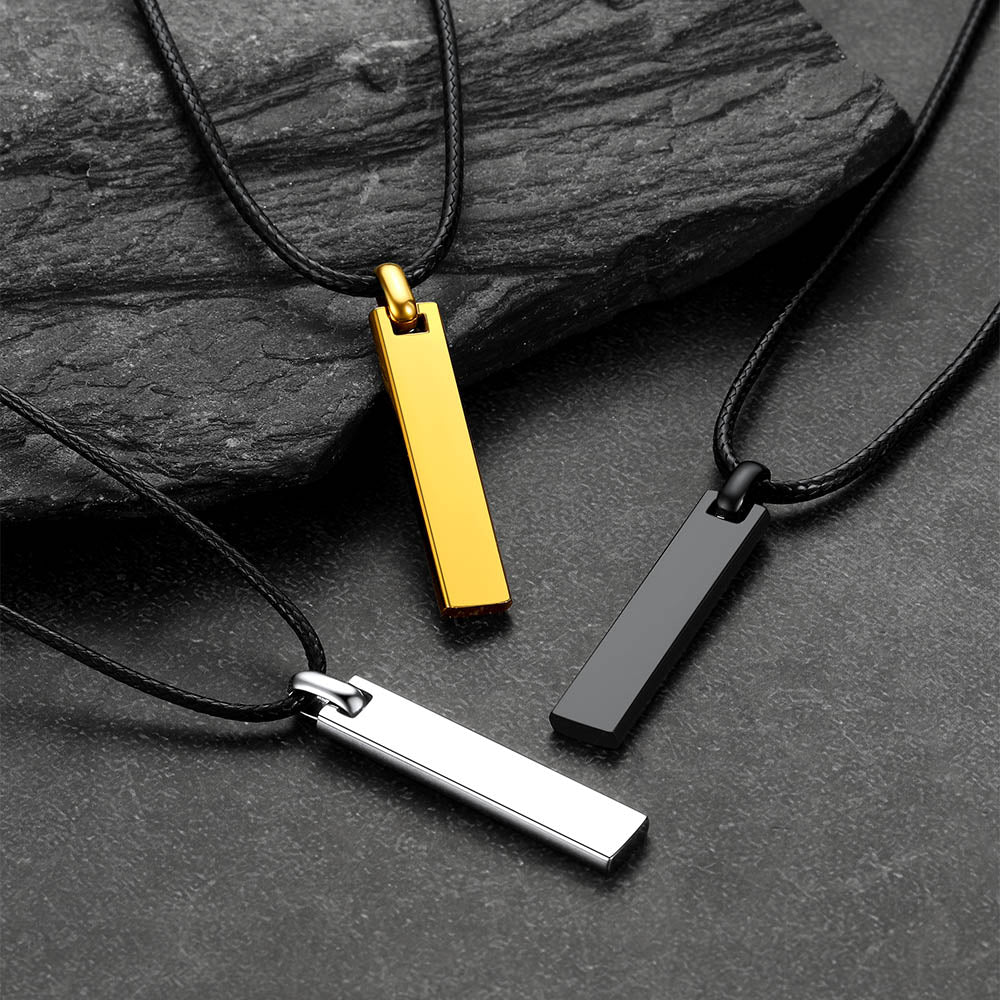 Three Bar Braided Leathernecklaces with gold, silver, and black pendants on a dark stone surface.
