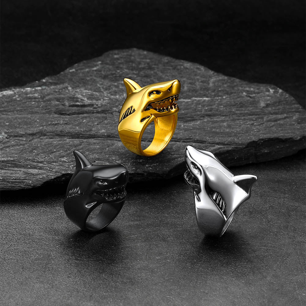 Three shark-shaped rings in gold, black, and silver
