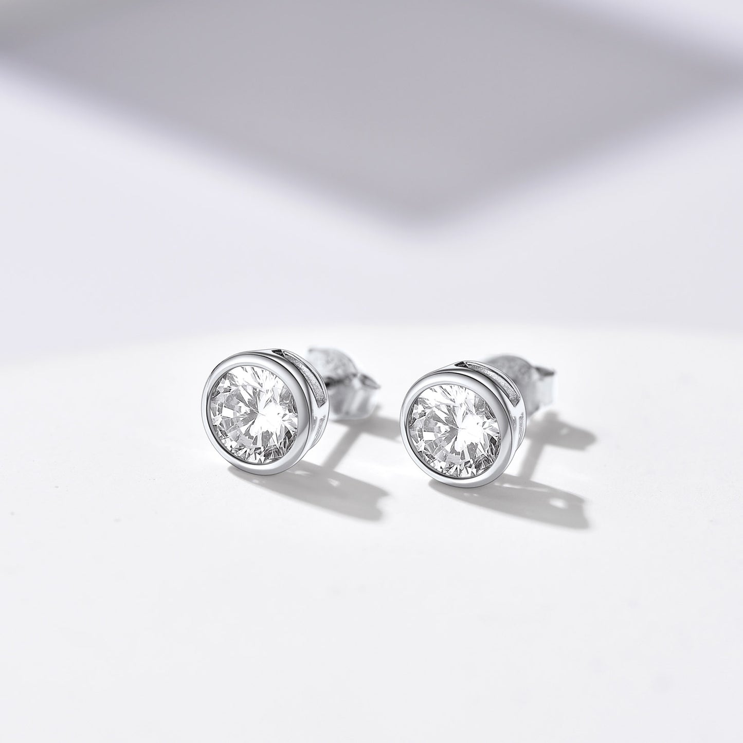 Pair of sterling silver cubic zirconia stud earrings on white surface.