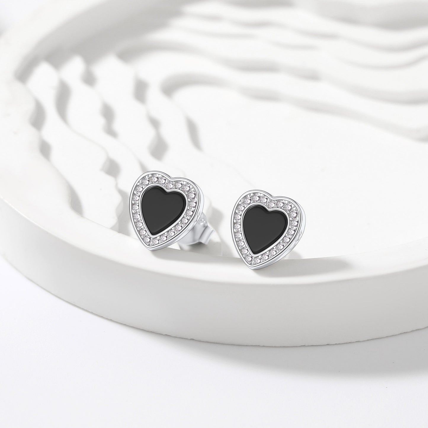 Heart-shaped earrings with black centers on a white dish