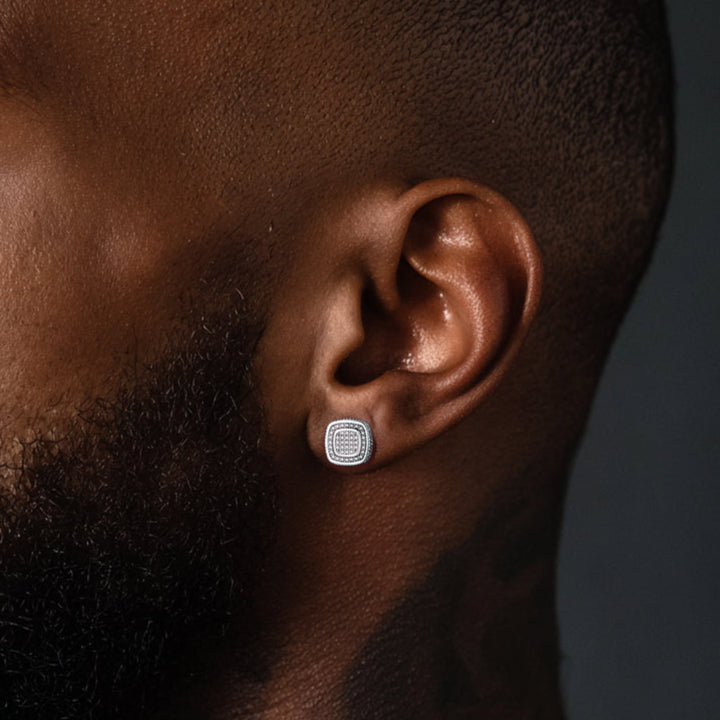Close-up of a man wearing a silver earring with a dark background