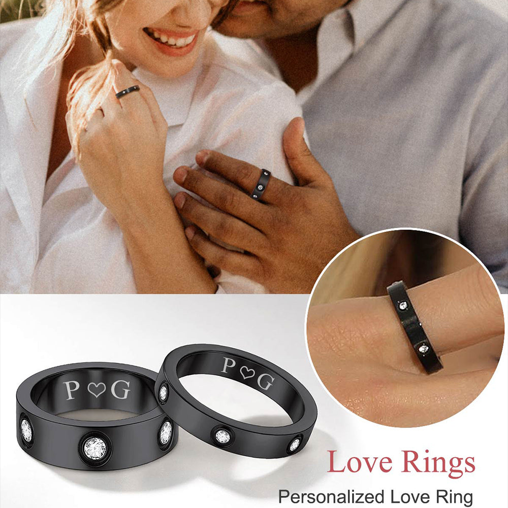 Black personalized love rings with 'P' and 'G' on a romantic background