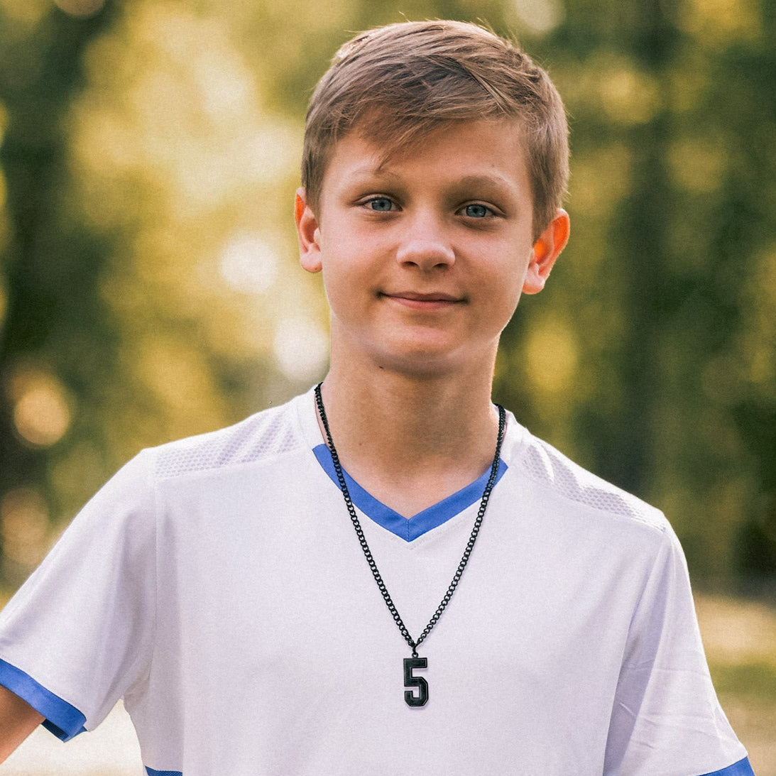 Boy wearing a sports jersey number 5 pendant necklace