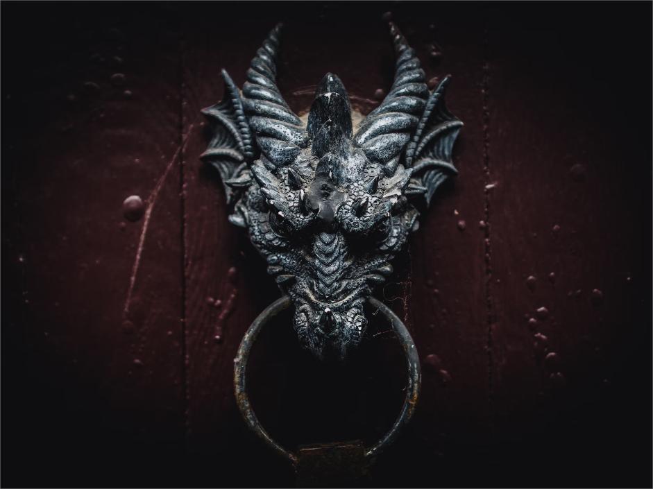 A close-up of a gothic dragon head door knocker on a dark red wooden door