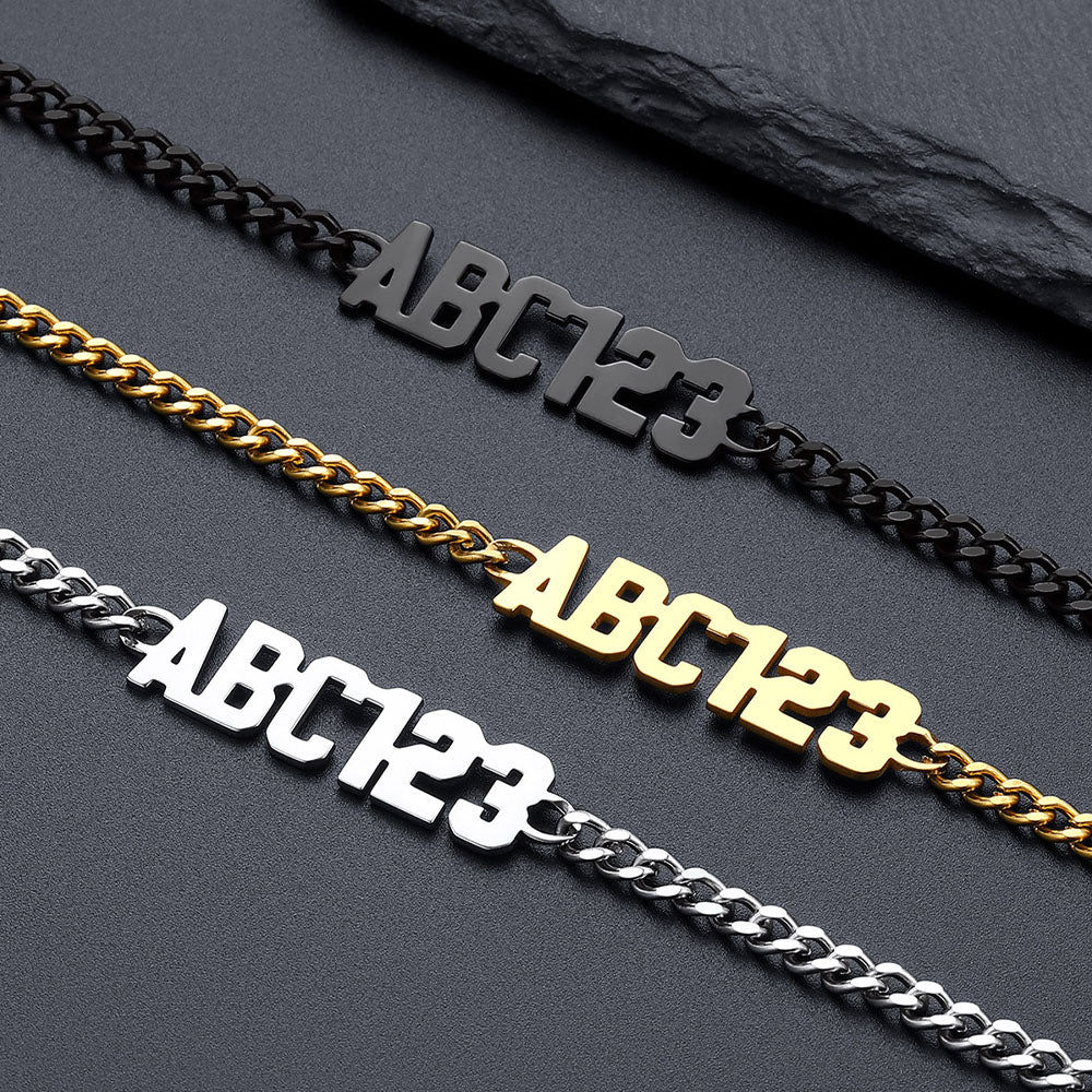 Three chain necklaces with 'ABC123' text in black, gold, and silver on a dark surface.