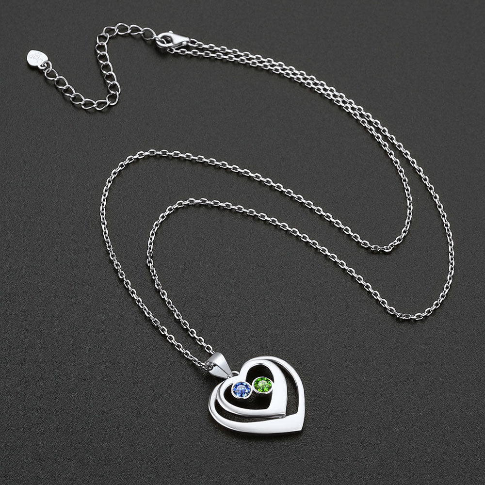 Silver heart-shaped pendant necklace with birthstone on a dark background