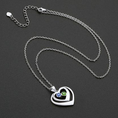 Silver heart-shaped pendant necklace with birthstone on a dark background