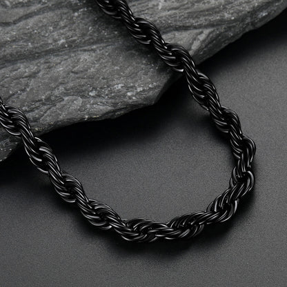 Black braided necklace on a dark surface with a stone background
