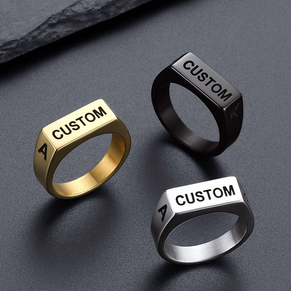 Three customizable rings in gold, black, and silver on a dark surface.