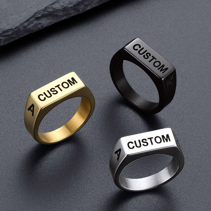 Three customizable rings in gold, black, and silver on a dark surface.
