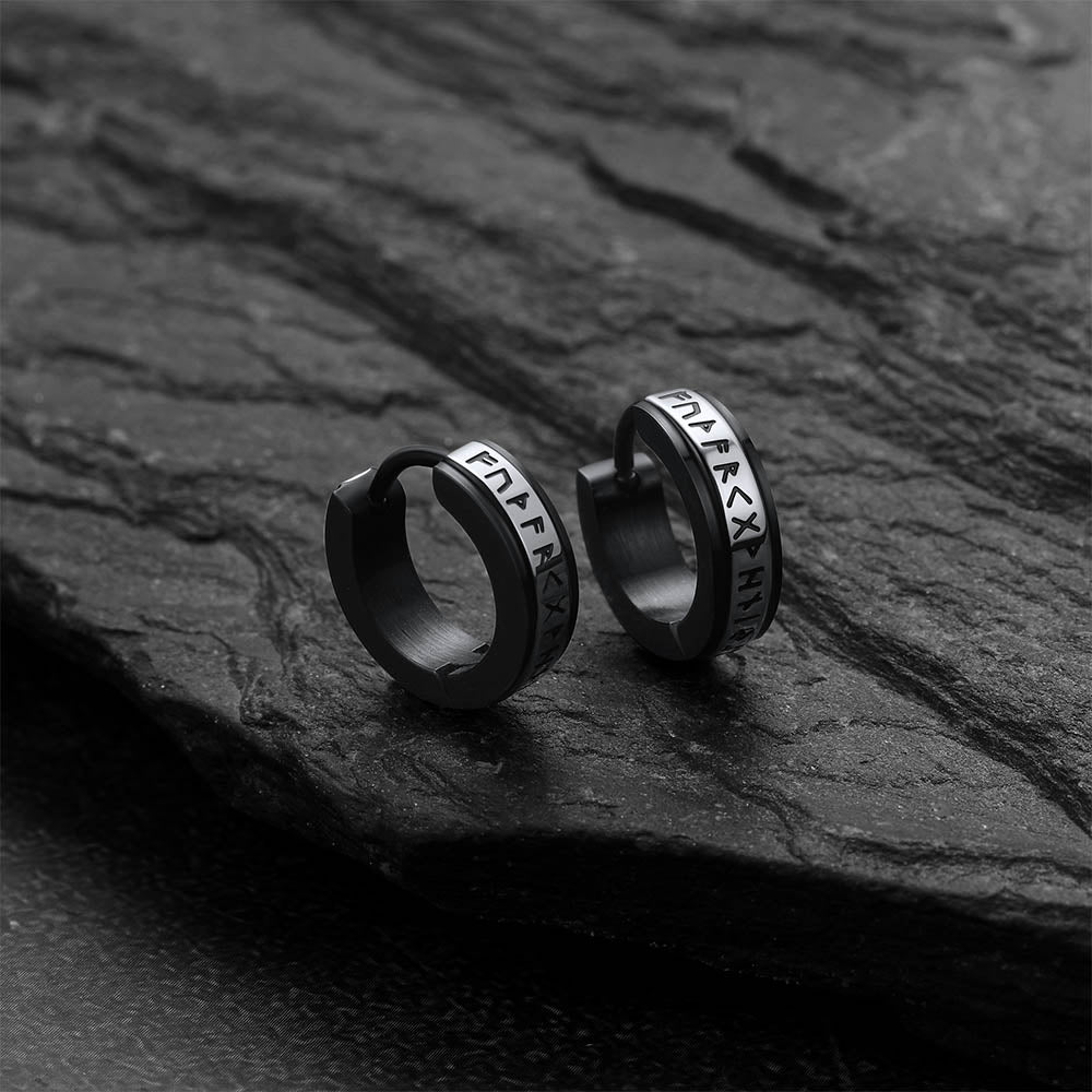 Black hoop earrings with viking rune on a dark stone surface