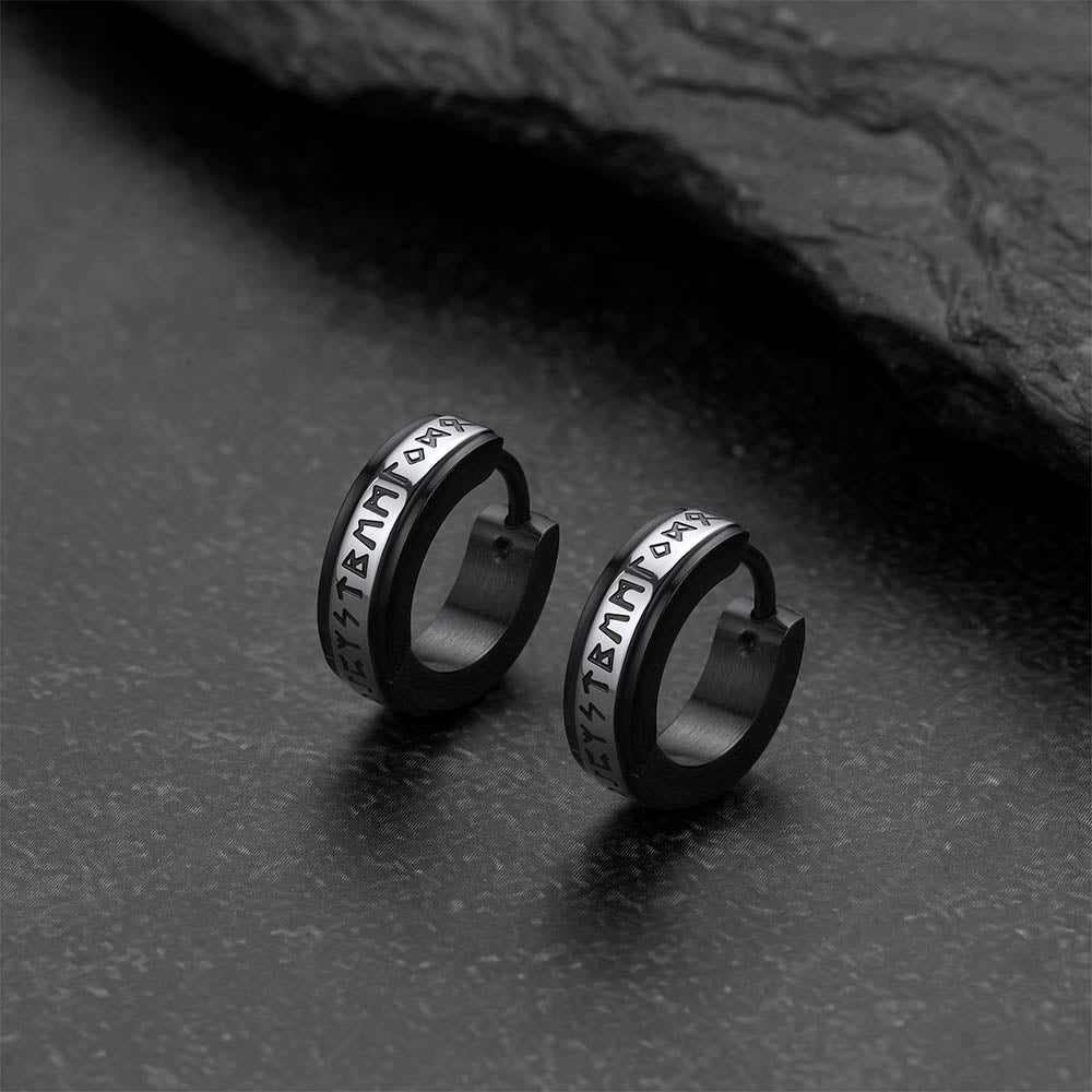 Pair of black hoop earrings with viking rune on a dark surface