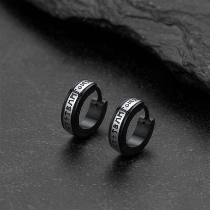 Pair of black hoop earrings with viking rune on a dark surface