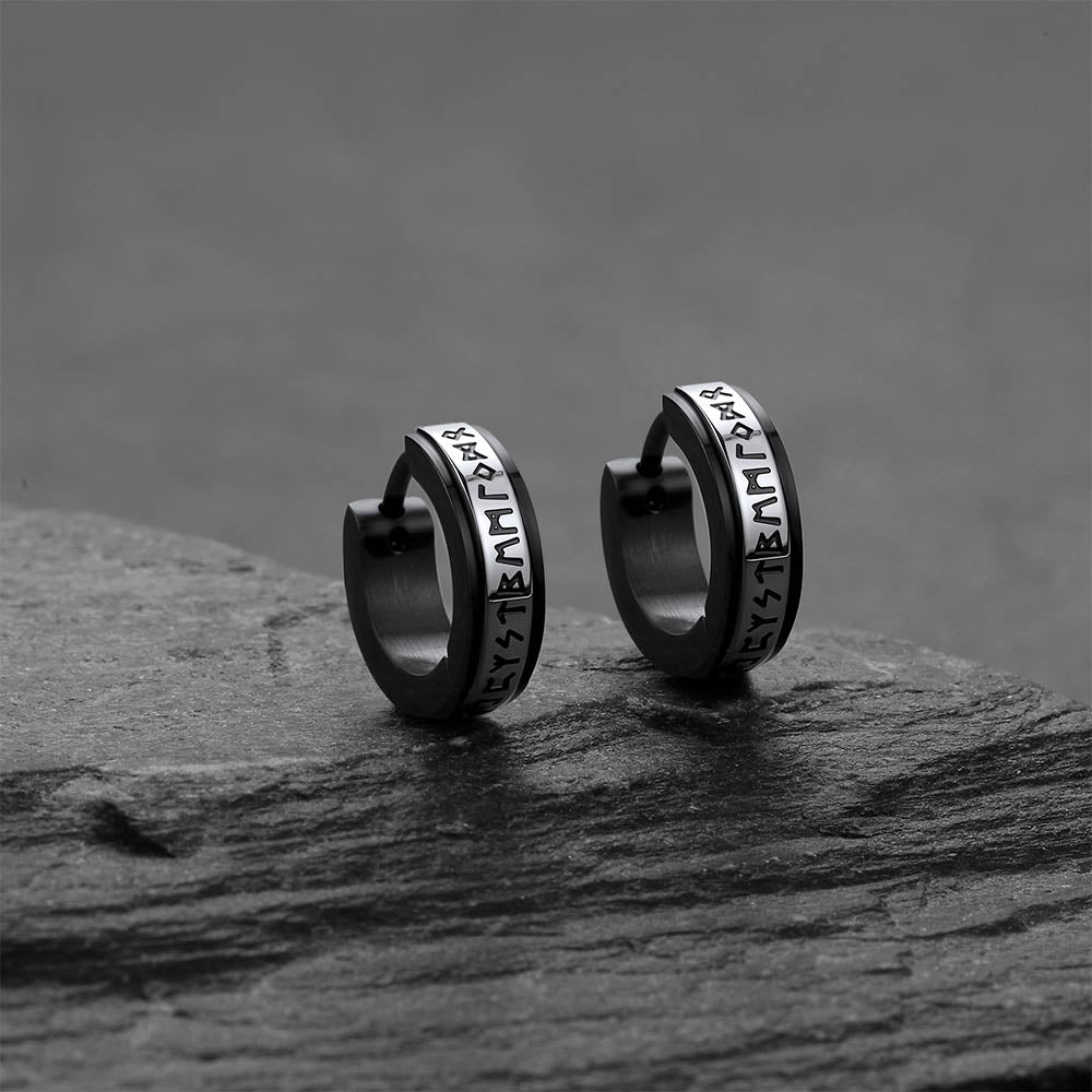 Black viking rune hoop earrings with engraved text on a dark stone surface