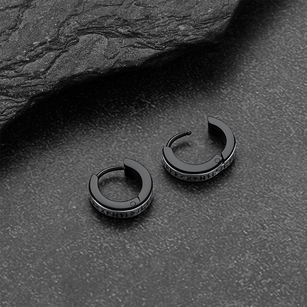 Black viking rune hoop earrings on a dark textured surface