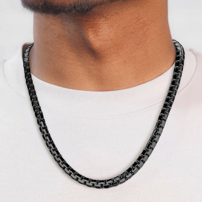 Black chain necklace worn by a person on a white background