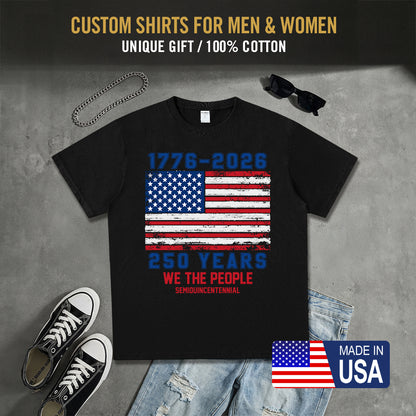 Black t-shirt with American flag design, sunglasses, sneakers, and jeans on a gray surface.