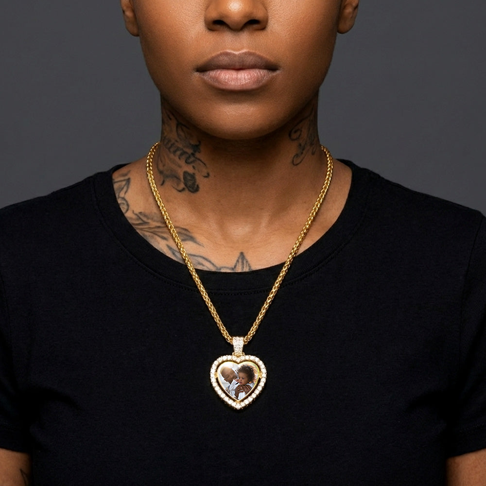 Person wearing a gold necklace with a heart-shaped pendant on a dark background