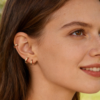 Woman wearing gold hoop earrings with a blurred outdoor background