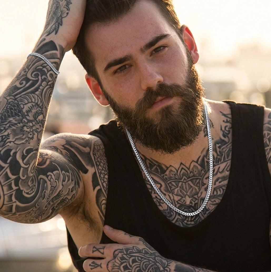 A man wearing a silver chain necklace and a chain bracelet.