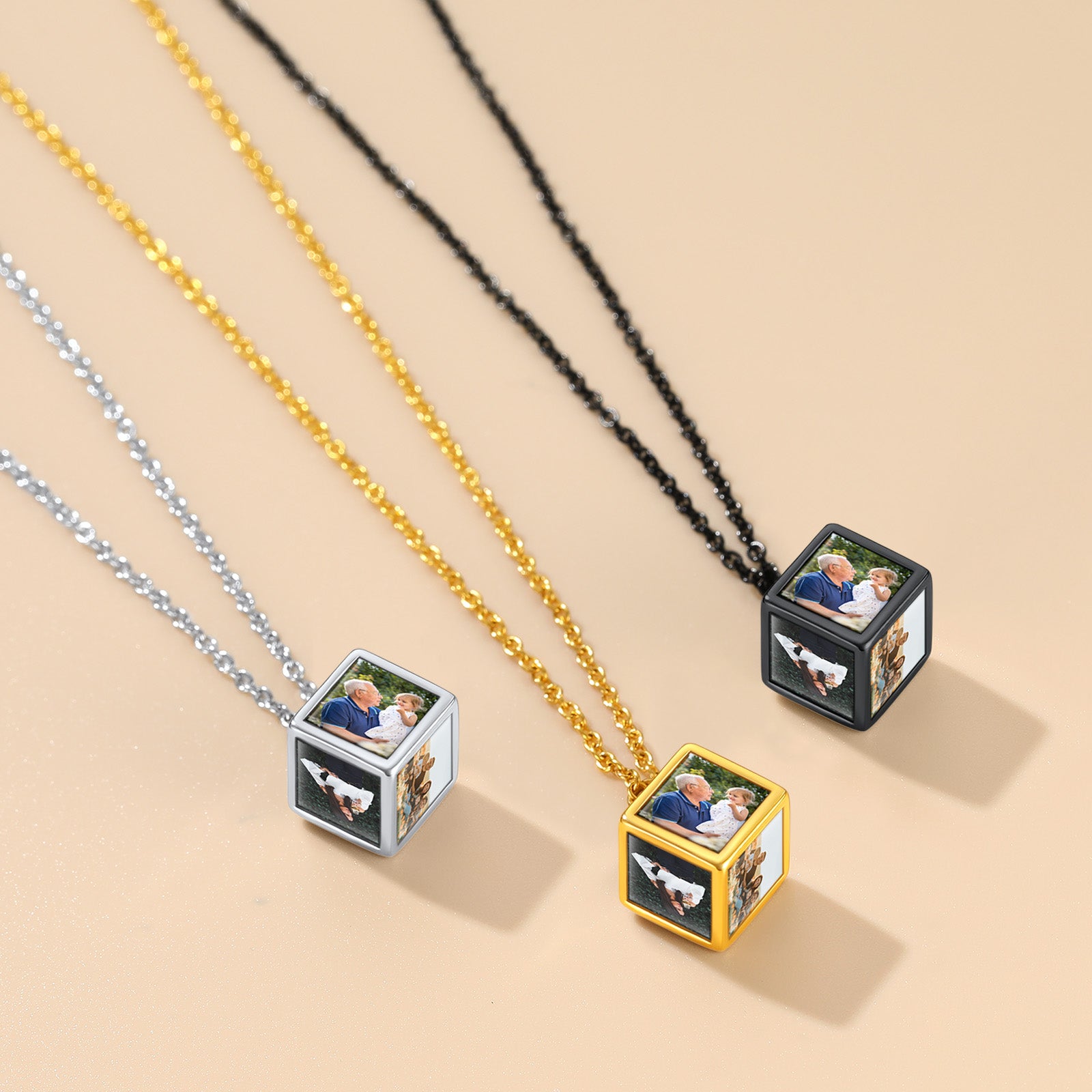 Three necklaces with cube pendants displaying family photos on a beige background