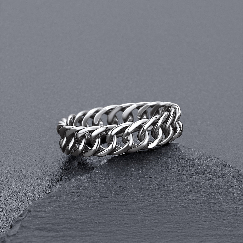 A silver-toned chain-link ring resting on a dark gray slate surface.